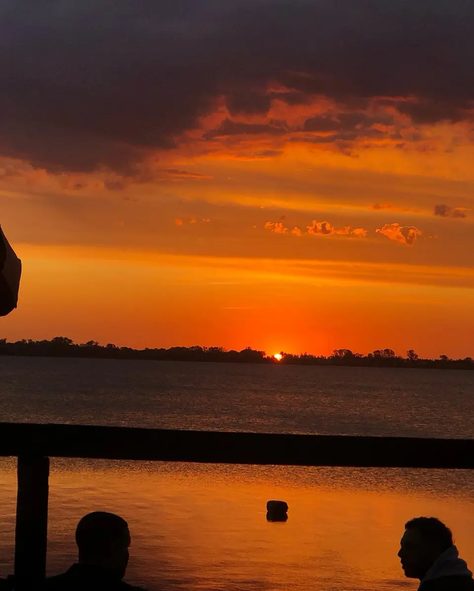 El sol que se pone sobre la laguna de Chascomús, con el cielo naranja.