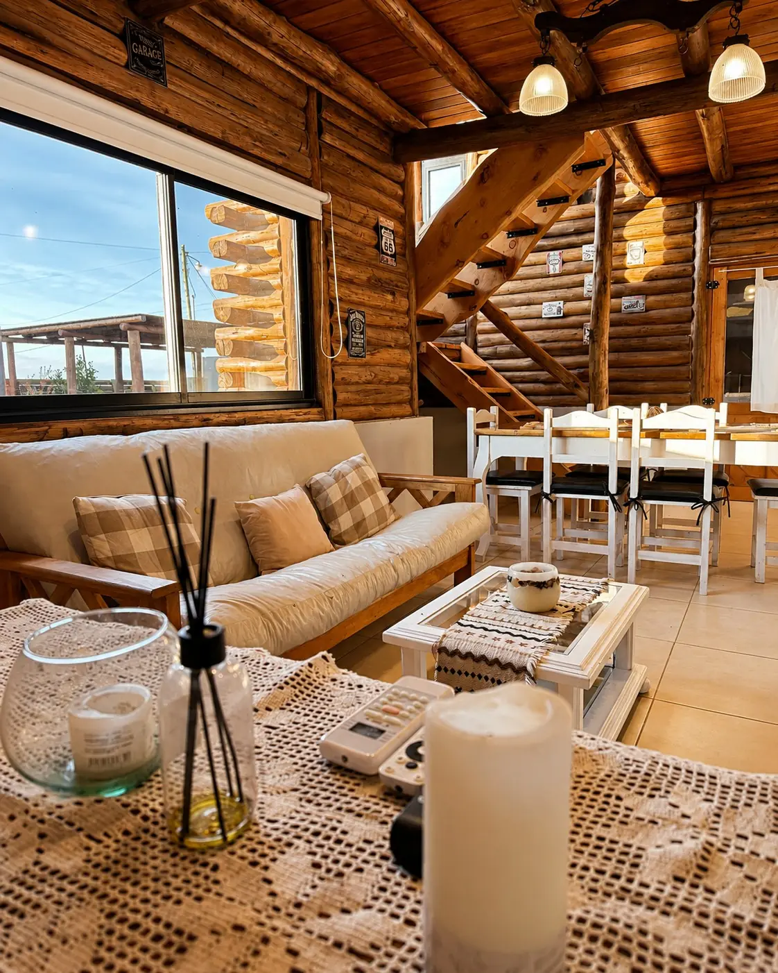 El living comedor de troncos, con la escalera de madera, la mesa blanca y el sillón.