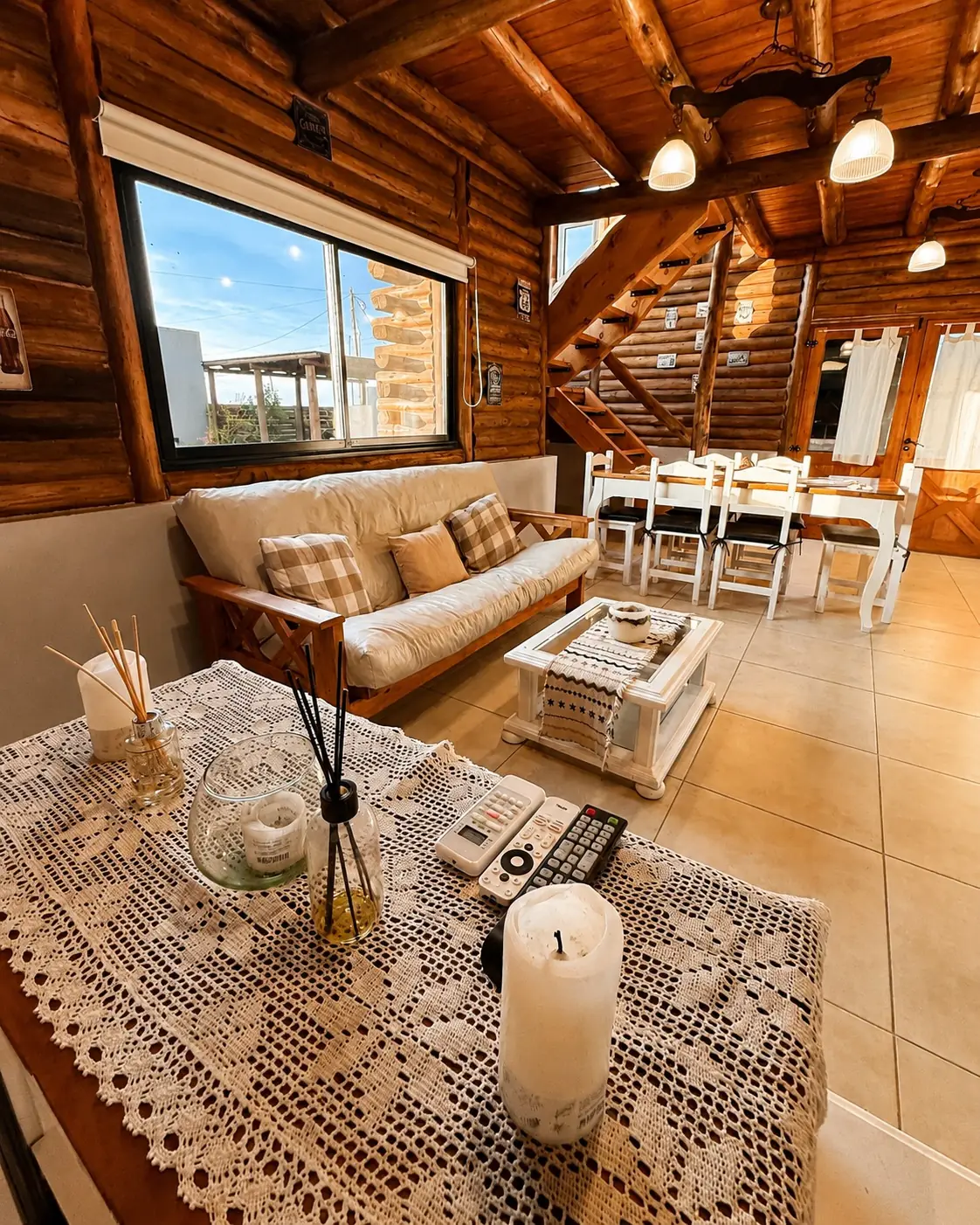 El living comedor de troncos con la luz de la tarde, el sillón y la mesa.
