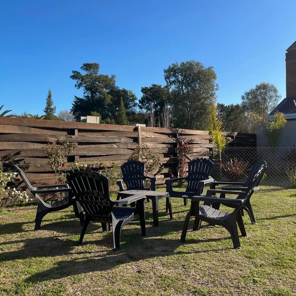 Los sillones del parque en ronda, sobre el pasto, con el cerco de madera atrás.