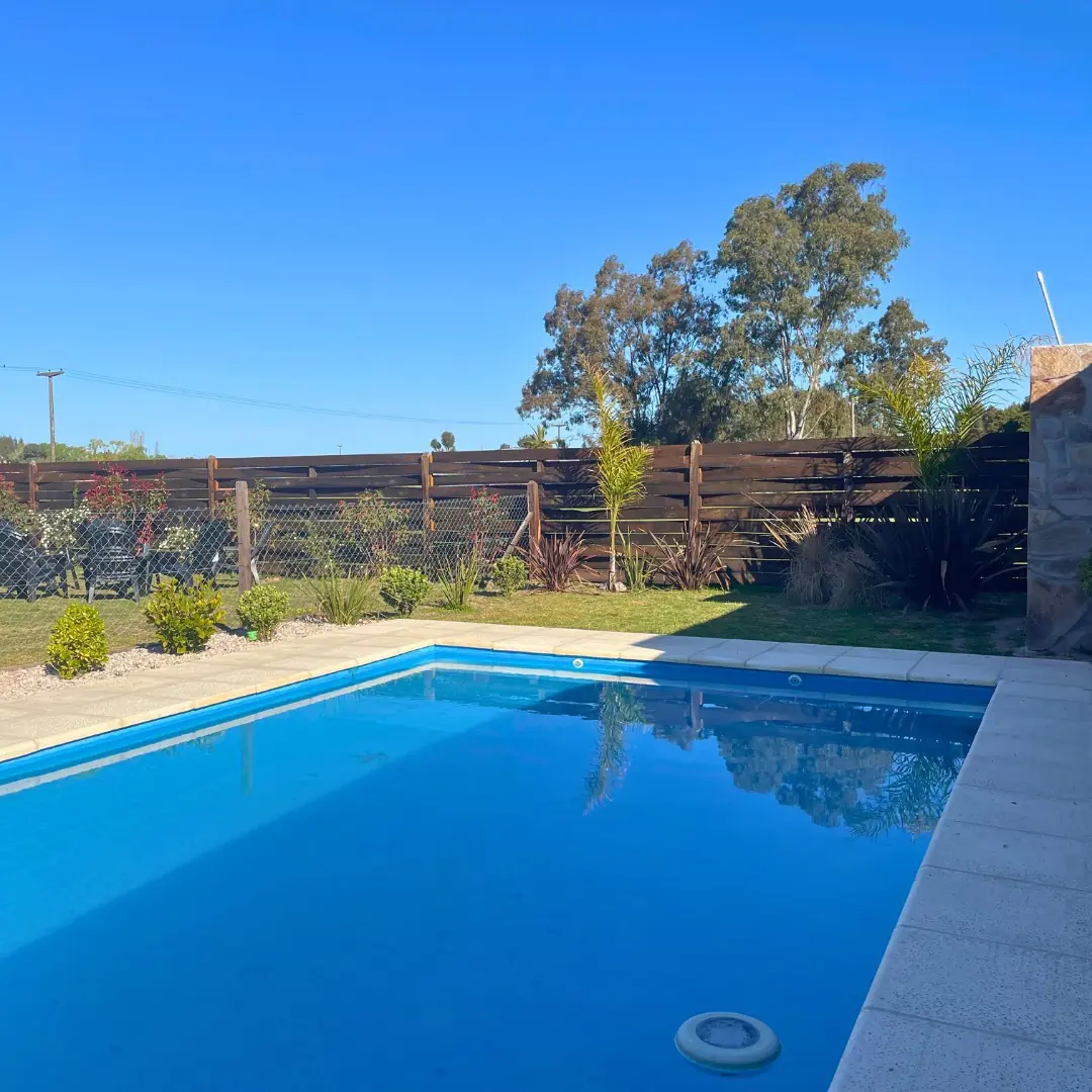 La pileta al mediodía, con el deck y las reposeras bajo la pérgola.